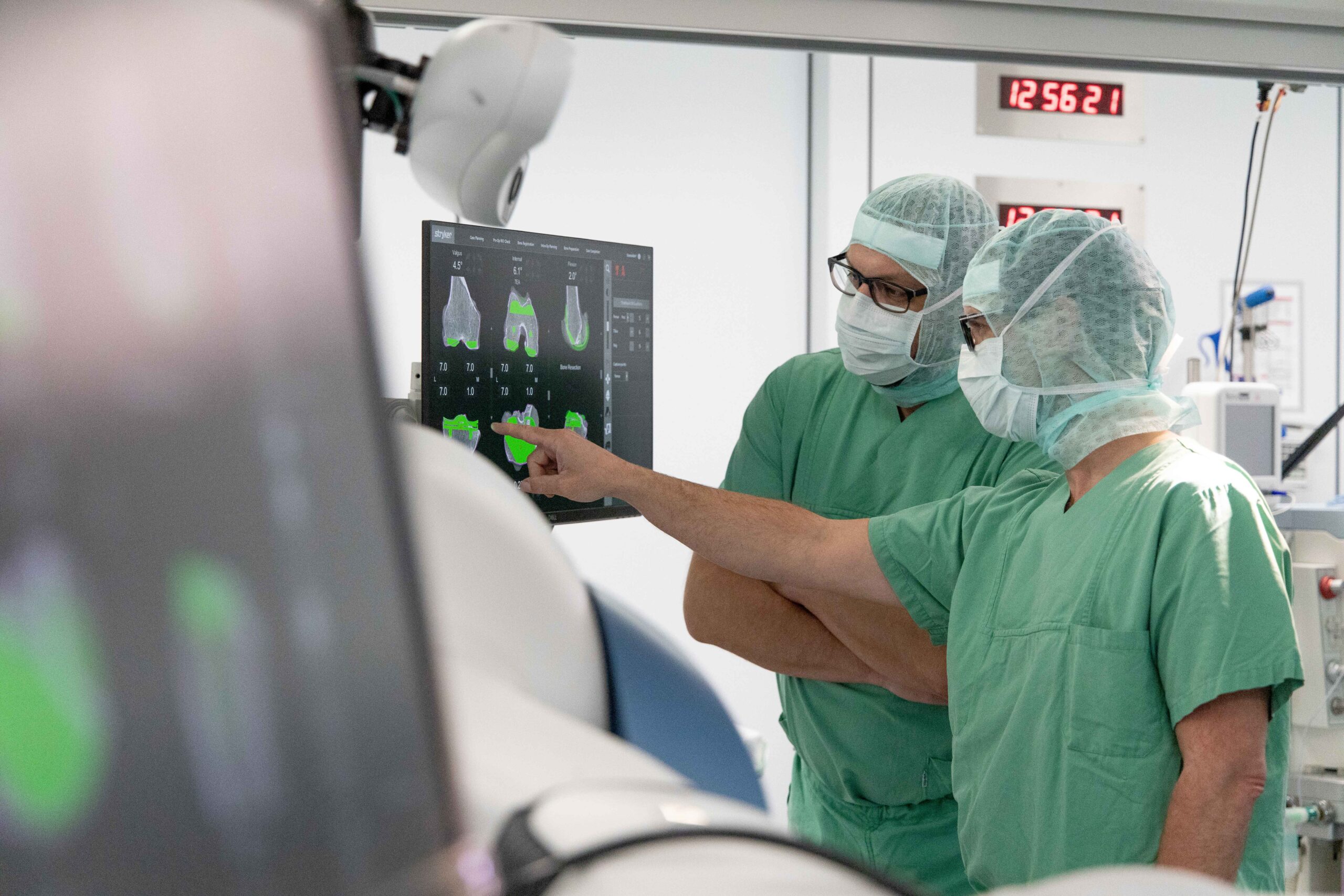Zwei Chirurgen stehen bei einer Knieoperation im OP