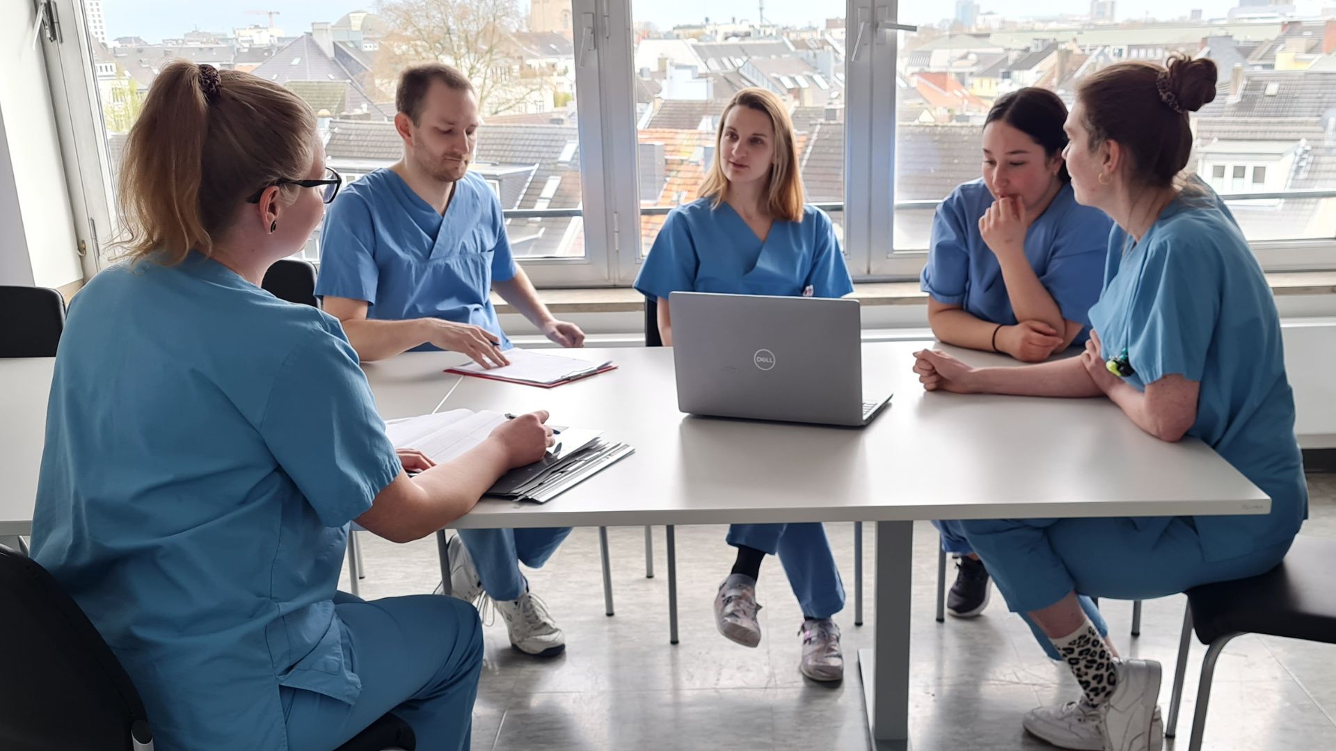 Fünf Pflegeexperten des Marien Hospital Düsseldorf sitzen um einen Tisch herum und beraten sich zur onkologischen Pflegevisite
