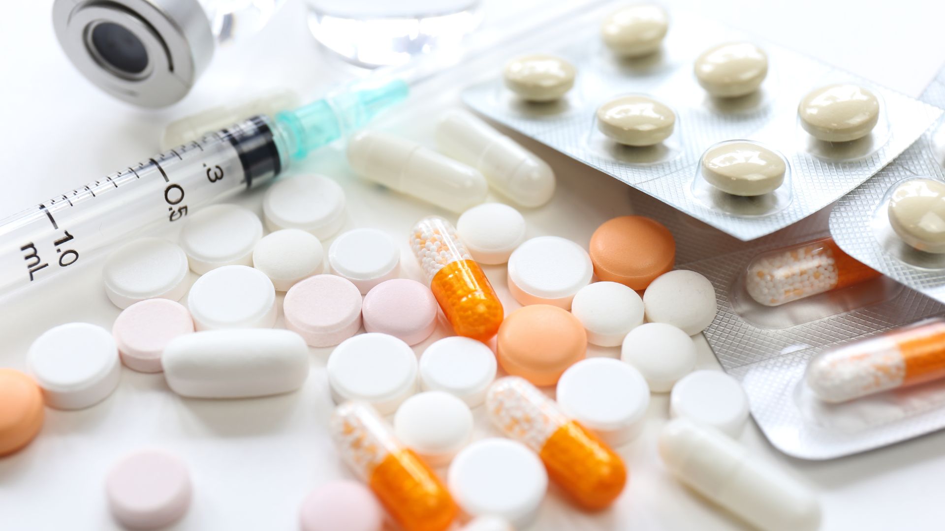 Tabletten, eine Spritze und Medikamentenfläschchen liegen verteilt auf einer Oberfläche