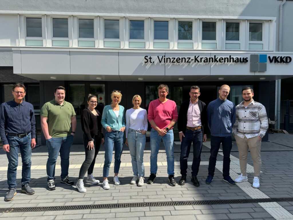 Einige Mitarbeiterinnen und Mitarbeiter der Abteilung Technik und Bau des VKKD stehen draußen vor dem Hauteingang des St. Vinzenz-Krankenhaus in Düsseldorf.