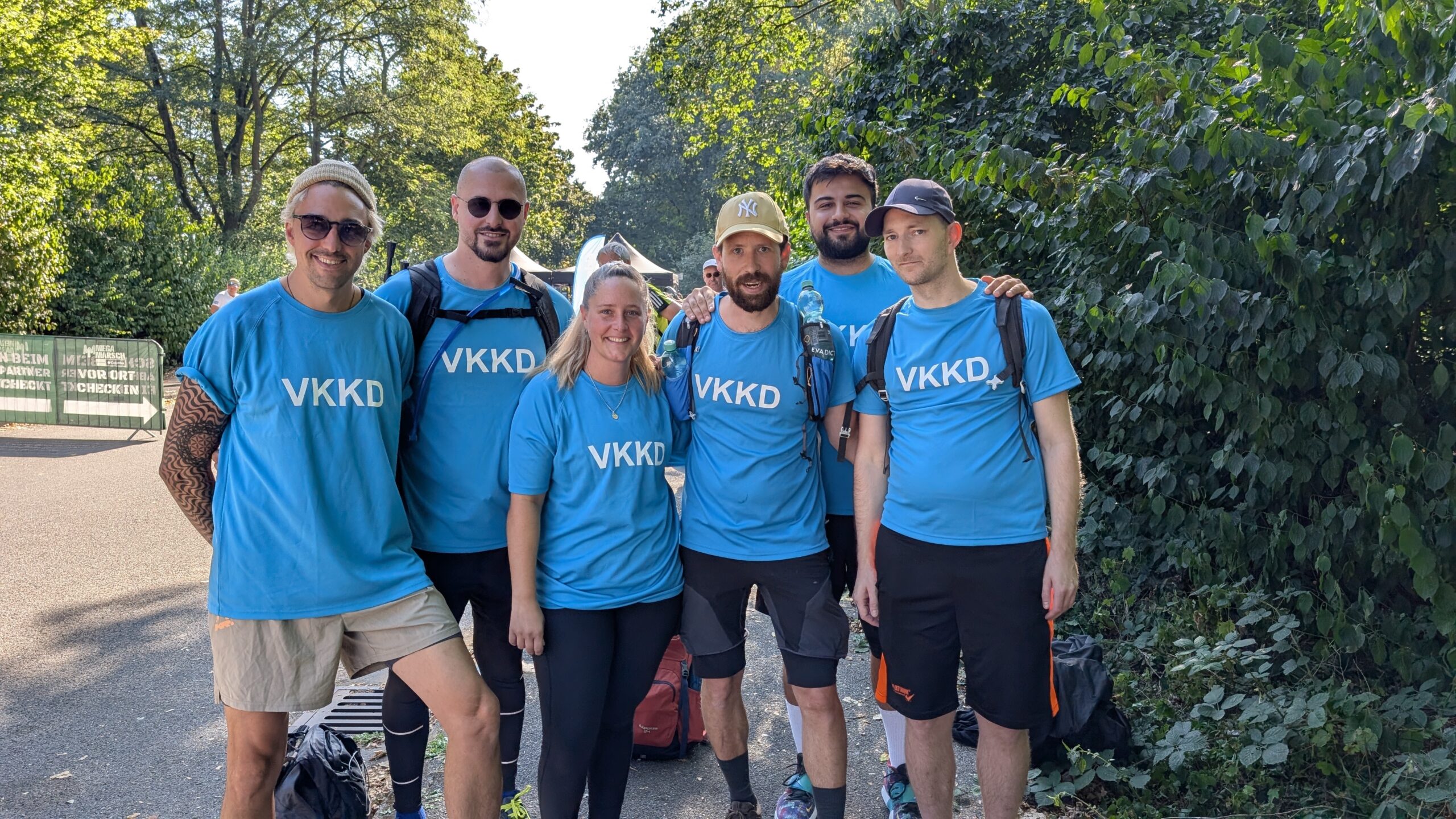 Die 6 Teilnehmer aus der Onkologie stehen in blauen VKKD-Shirts nebeneinander vor dem Start des Megamarschs